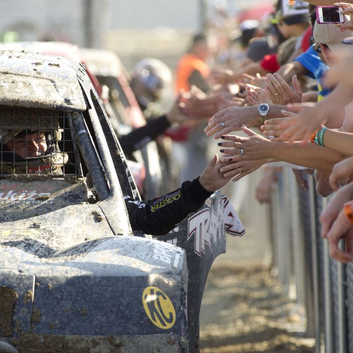 Driver high-fiving a line of fans