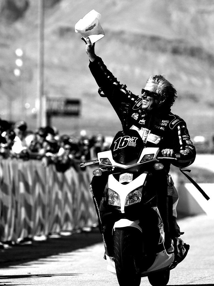John Force waving to fans from his motorcycle
